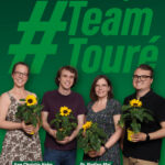 Aus Pinneberg für Team Touré! Foto von Ann Christin Hahn, Luca Moriconi, Dr. Nadine Mai und Lukas Unger, die zusammen stehen und jeweils eine Sonnenblume in der Hand halten.